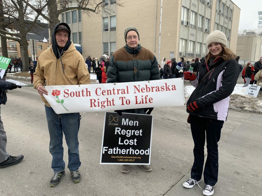 group of pro life members of South Central Nebraska Right to Life hold a pro-life sign at the nebraska walk for life 2019 in lincoln, nebraska