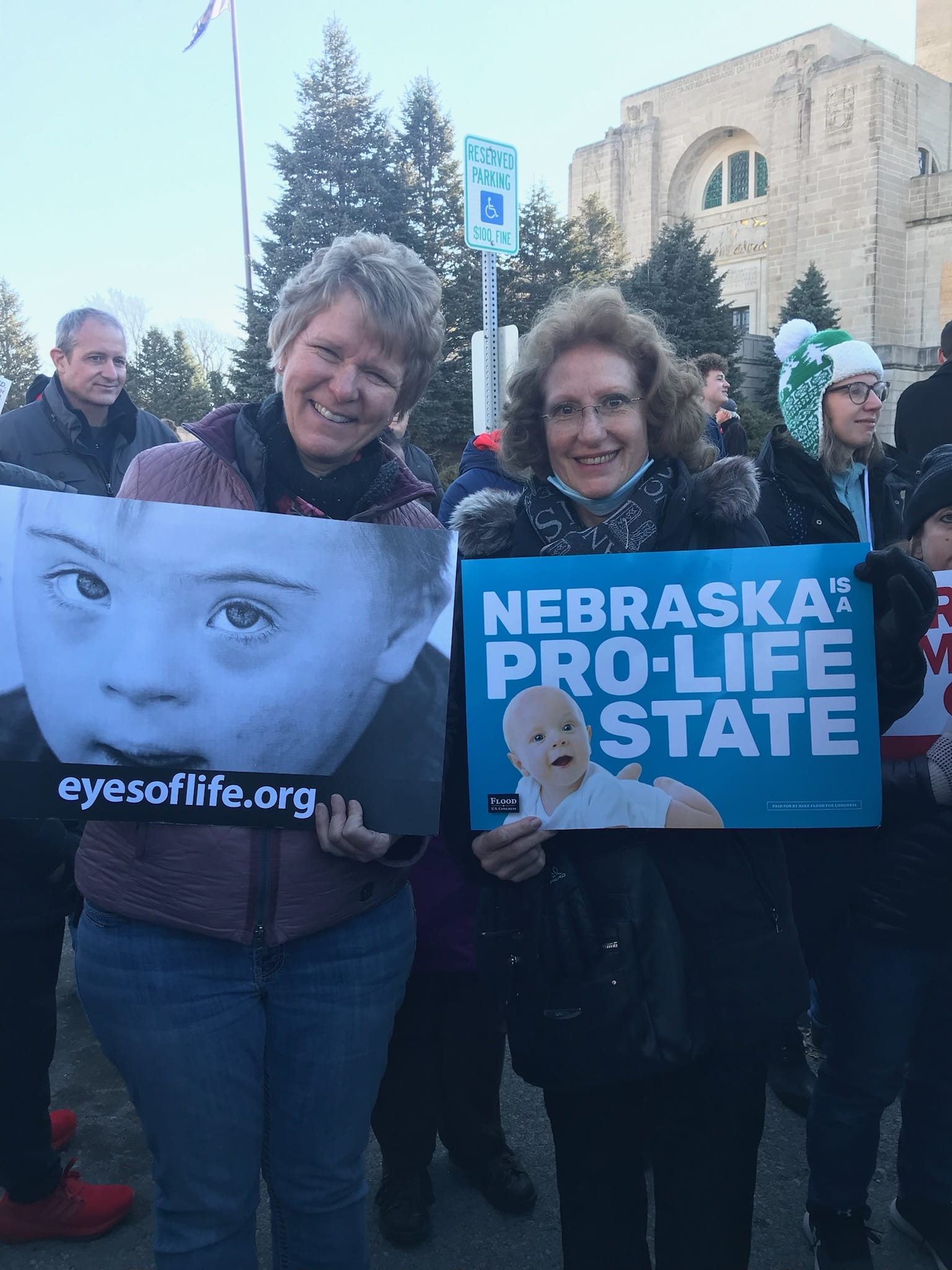 two women stand with prolife signs in lincoln nebraska at a march